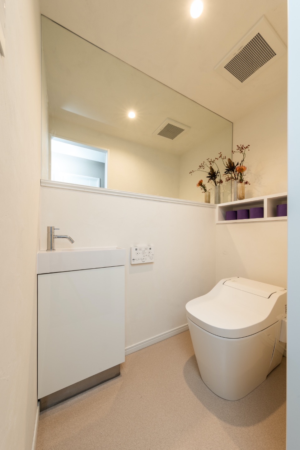 壁を漆喰で仕上げ消臭性と調湿性を高めたトイレ。幅いっぱいのミラーで広く見える工夫も。