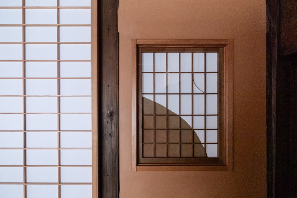 玄関の壁はすべて大津仕舞仕上げ。小窓は金魚すくいのポイを使い、月をイメージしたデザインに。