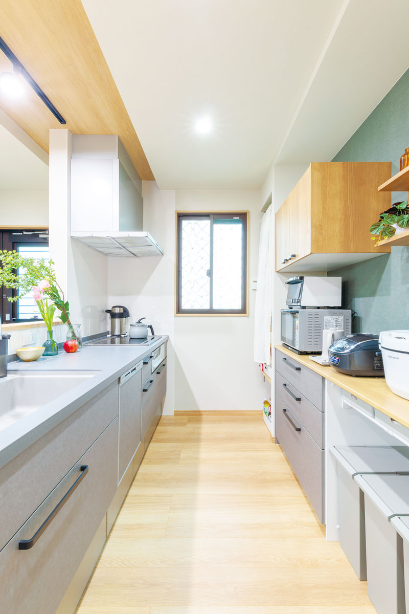 元のトイレの小窓を中心に、薄いグレーのキッチンとカップボードを配置