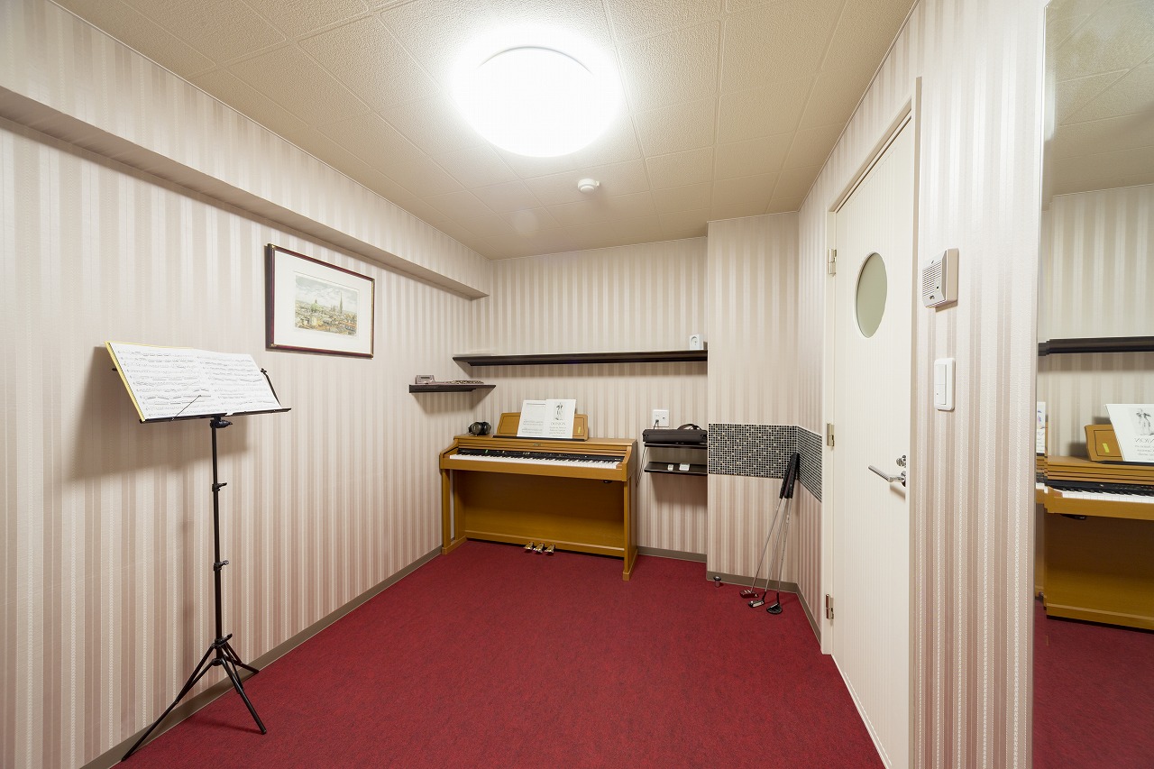 防音室は壁一面に音の吸収率が高い布クロスを使用。赤いフロアカーペットはゴルフのパター練習もできます。