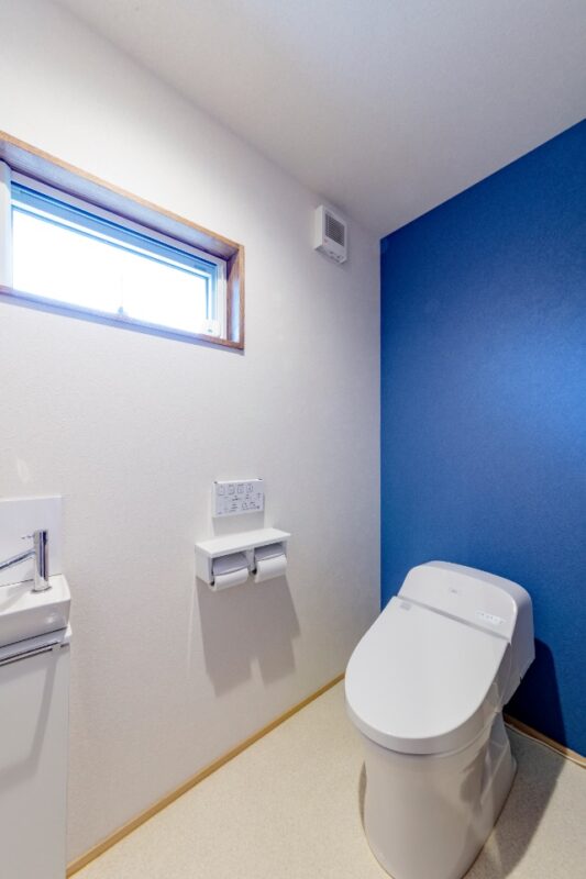 水廻りはすべて窓が取れる場所に設置。トイレは引き戸で出入りしやすく、ブルーを効かせて爽やかに。
