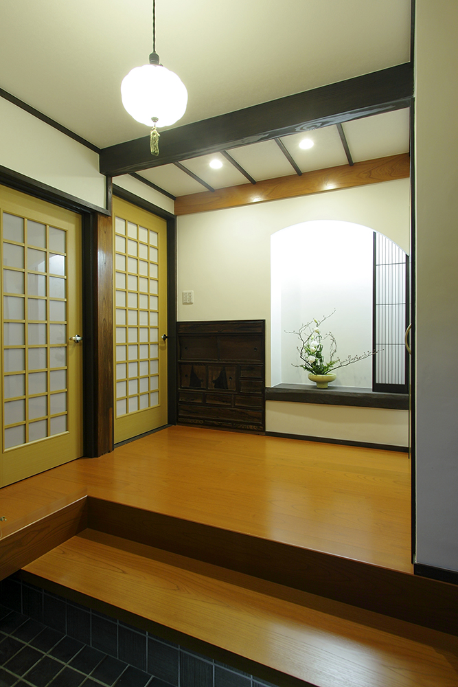 古い梁をカウンターとして再利用し、珪藻土や格子を用いた飾り棚で和の趣を演出した玄関。