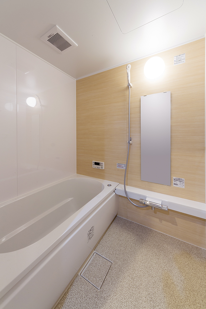 浴室はナチュラルカラーな木目風の壁を選択。洗面室との雰囲気の繋がりも。