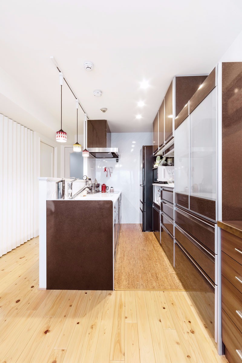 システムキッチンとカップボードは茶色で統一。床は汚れに強いセラミックのコルクタイルを